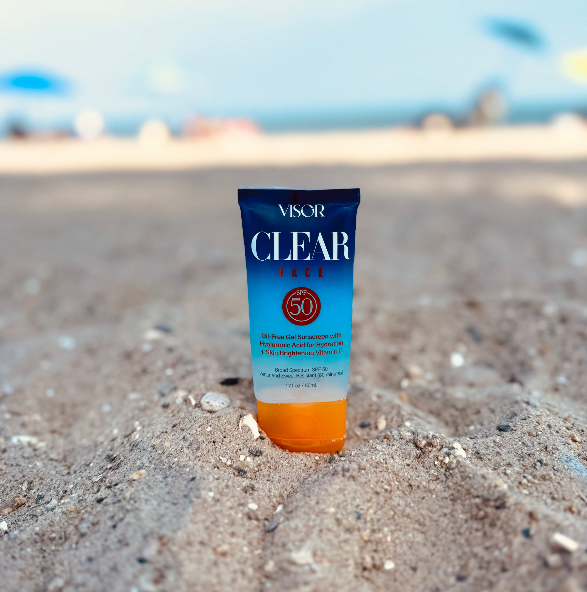 Visor Clear Face sunscreen tube on sand with blurred beach background