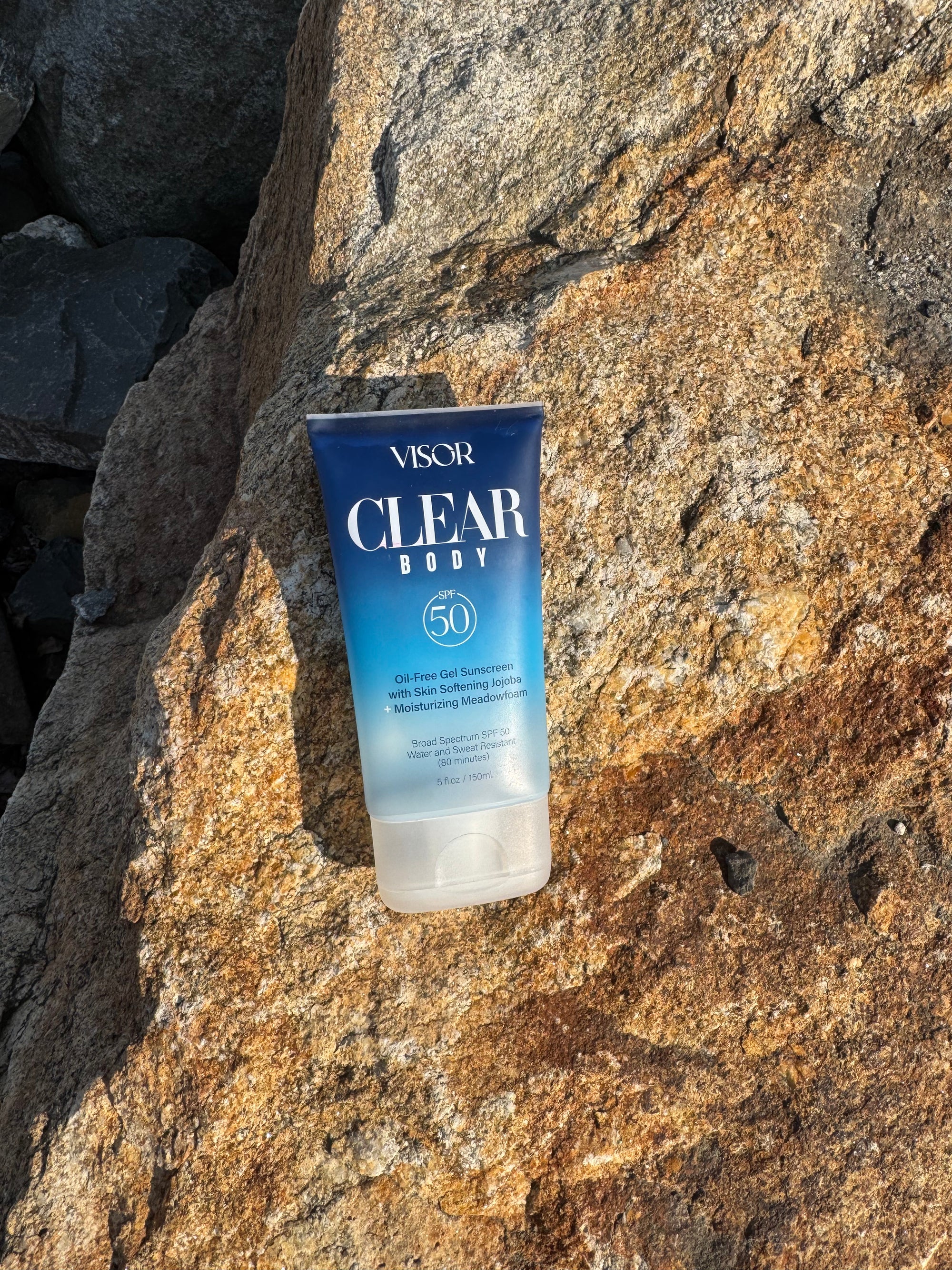 Visor Clear Body sunscreen tube on a rocky surface
